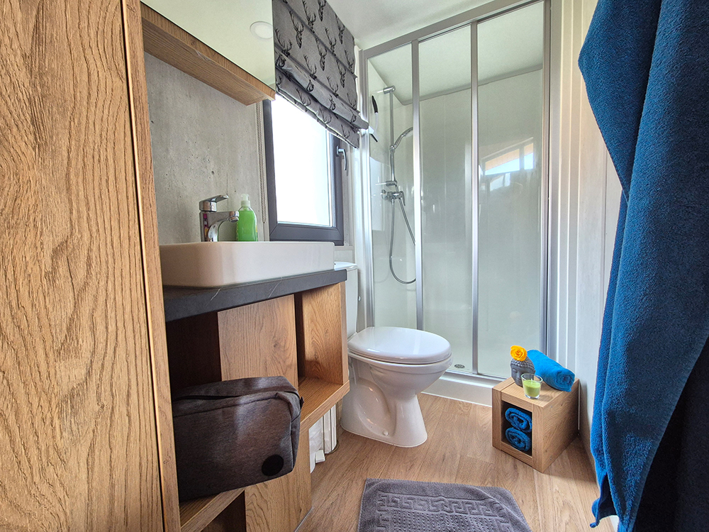 Modernes Badezimmer im Alpenchalet Wendelstein mit Glasdusche, Holzwaschtisch und alpinem Dekor zum Entspannen und Wohlfühlen.